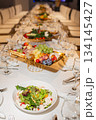 Wide shot of long set table with appetizer and salad assortment - elegant buffet 134145427