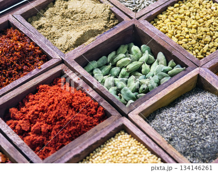 Colorful spices arranged in wooden boxes at a market in the afternoon sun for cooking and flavoring meals 134146261