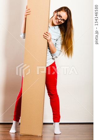 Happy woman moving into apartment carrying box. 134146580