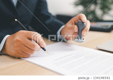 Businessman signing and stamping official document at desk, concept of legal contract approval, authorization or business agreement confirmation in corporate office background. stamp approval 134146591