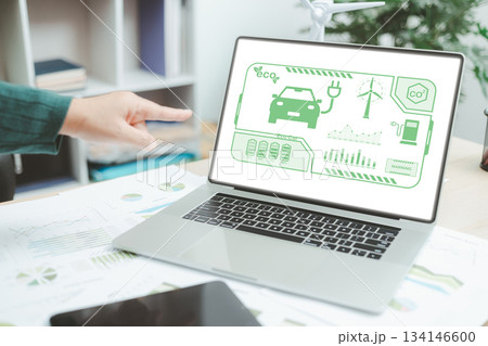 Laptop screen showing eco car dashboard with battery level, wind turbine and CO2 data, representing electric vehicle technology, green energy innovation and sustainable transportation concept. Laptop screen showing eco car dashboard with battery level, wind turbine and CO2 data, representing electric vehicle technology, green energy innovation and sustainable transportation concept. 134146600