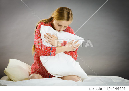 Sad depressed girl in bed gripping pillow 134146661