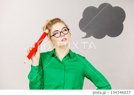 Woman holding big oversized pencil thinking 134146837