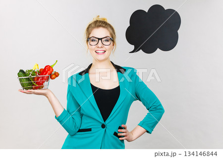 Woman holds shopping cart with vegetables, copy space Woman holds shopping cart with vegetables, copy space 134146844