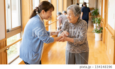 介護士が高齢女性を優しく支援しながら歩行を見守る介護施設のひとこま 134148196