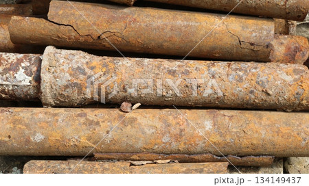 Old used rusty iron pipes with cracks and growths lying in a pile, background industrial rough texture, waste water supply system pipes, replacement of old unusable water supply system 134149437