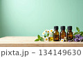 ミントグリーン背景に並ぶエッセンシャルオイル瓶とカモミール・ハーブ 134149630