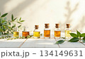 明るい木製テーブルに並ぶエッセンシャルオイル瓶とグリーンのボタニカル素材 134149631