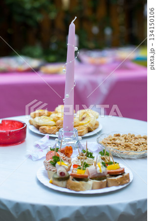 Wedding reception decorated table showing delicious appetizers and a pink candle 134150106