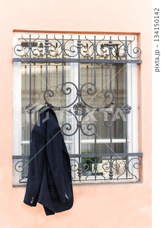 Groom's jacket hanging from a window with decorative metal bars during wedding preparations 134150142
