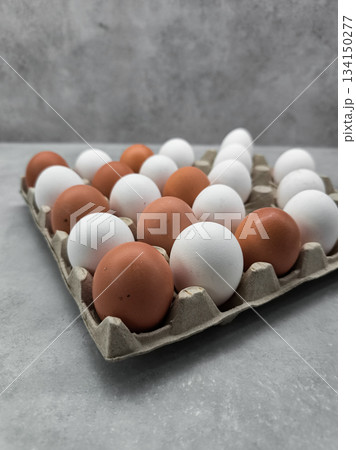 Brown and white eggs resting in carton on gray table easter 134150277