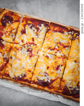 Delicious homemade square pizza with salami, peppers, and melted cheese Delicious homemade square pizza with salami, peppers, and melted cheese 134150345