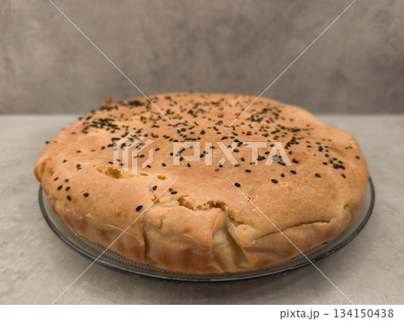 Delicious homemade pie sprinkled with black sesame seeds on glass plate copy space gray background Delicious homemade pie sprinkled with black sesame seeds on glass plate copy space gray background 134150438