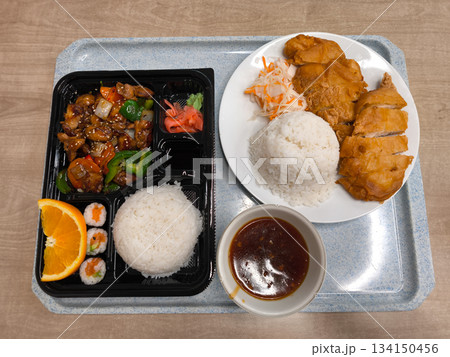 Delicious asian food served on tray with rice, chicken, and sushi rolls bento lunch fast food 134150456