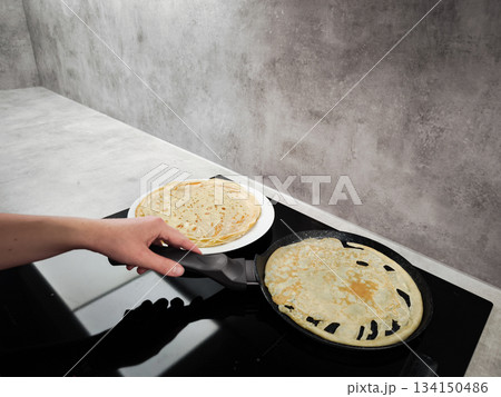 Chef preparing crepes on induction cooker for shrove tuesday, maslenitsa or breakfast celebration Chef preparing crepes on induction cooker for shrove tuesday, maslenitsa or breakfast celebration 134150486