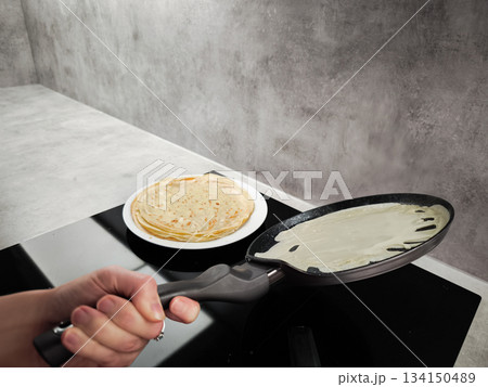 Woman cooking crepes on a non stick pan in prague for shrove tuesday, maslenitsa or breakfast Woman cooking crepes on a non stick pan in prague for shrove tuesday, maslenitsa or breakfast 134150489