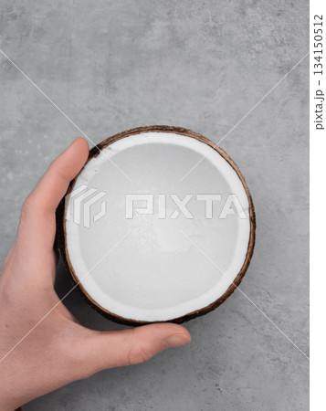 Hand holding half a coconut on gray background. Copy space, banner Hand holding half a coconut on gray background. Copy space, banner 134150512