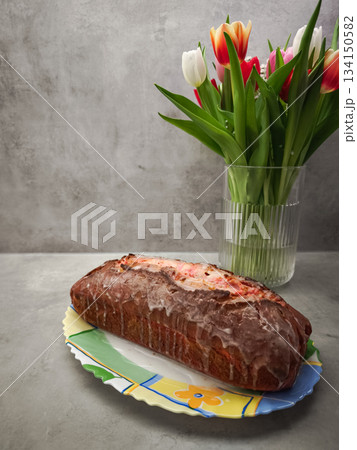 Sweet pink frosted loaf marble cake sitting on floral plate, nestled near soft tulip blooms, representing romantic prague breakfast setting 134150582