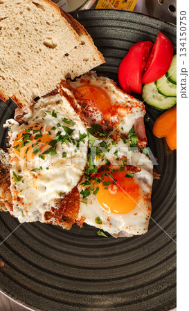 Fried eggs with ham, bread, and vegetables for breakfast in slovakia strbske pleso, high tatras 134150750