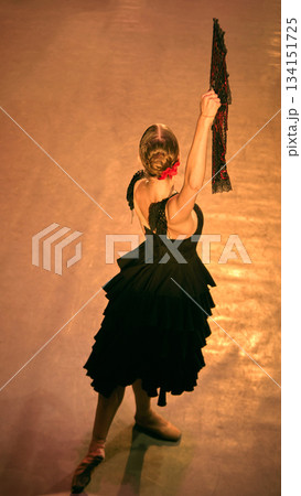 Dancer extending fan overhead in elevated stage view. 134151725