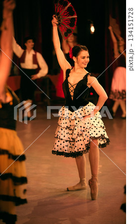 Ballet performer raising decorative fan in spotlight. Ballet performer raising decorative fan in spotlight. 134151728