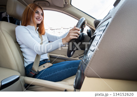 Young redhead woman driver driving a car smiling happily. 134152620