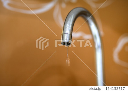 Water tap, chrome stainless metal faucet with running stream of water in bathroom or kitchen, mixer cold hot water isolated on bright yellow copy space background. Modern kitchen interior. 134152717