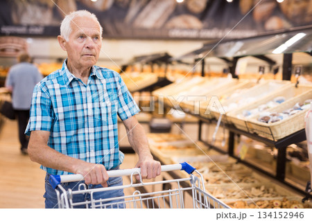 old age senor examines bakery products in the grocery section of the supermarket old age senor examines bakery products in the grocery section of the supermarket 134152946