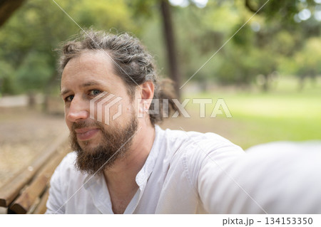 Smiling man taking selfie in green park Smiling man taking selfie in green park 134153350