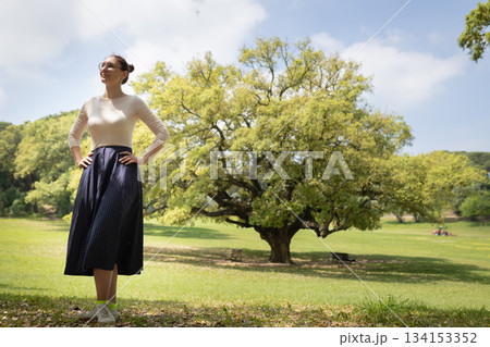 Woman standing in park looking up at sky Woman standing in park looking up at sky 134153352