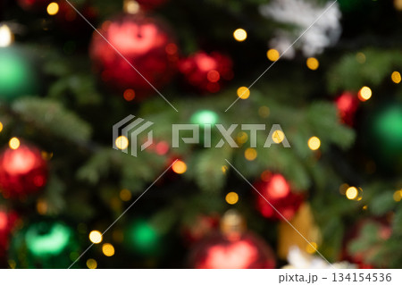 Blurred Christmas tree with red and golden balls and lights garland. Abstract pattern. Defocused background. Xmas holiday spirit. Blurred Christmas tree with red and golden balls and lights garland. Abstract pattern. Defocused background. Xmas holiday spirit. 134154536