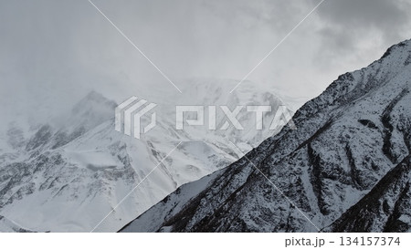 Snow-covered mountain peaks under cloudy sky with dramatic landscape 134157374