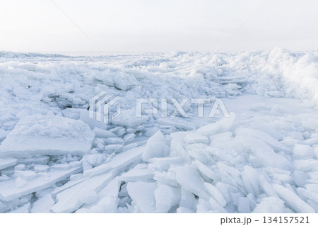 A bright icy shoreline features jagged white ice shards piled along the coast A bright icy shoreline features jagged white ice shards piled along the coast 134157521