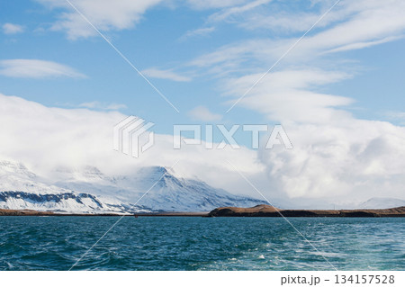 Mountains covered with snow meet a deep blue sea in a tranquil wintry landscape 134157528