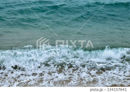 Close-up of soft waves sand beach and blue sea. Texture of water, white foam waves. Seascape, Sea background, Sea water with copy space, summer vacation concept. Close-up of soft waves sand beach and blue sea. Texture of water, white foam waves. Seascape, Sea background, Sea water with copy space, summer vacation concept. 134157641