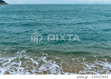 Close-up of soft waves sand beach and blue sea. Texture of water, white foam waves. Seascape, Sea background, Sea water with copy space, summer vacation concept. Close-up of soft waves sand beach and blue sea. Texture of water, white foam waves. Seascape, Sea background, Sea water with copy space, summer vacation concept. 134157643