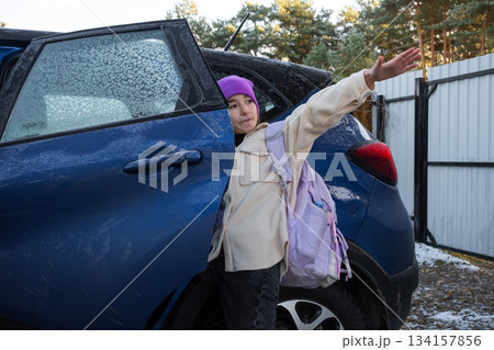 A girl with a backpack gets into a car to get to school 134157856