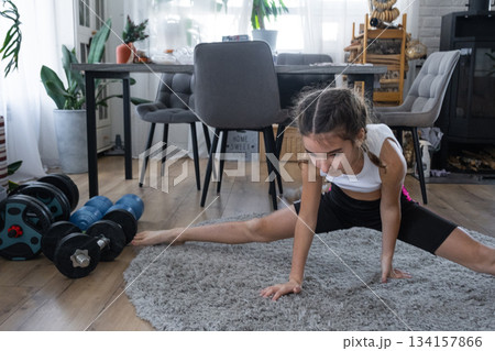 A girl does a splits stretch at home, gymnastics training 134157866