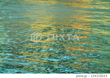 Reflection of city light on water at night. Night sea view with street light. Light hitting on the ocean.Sea background. Background of the calm water, water waves. Sea water surface. 134158033