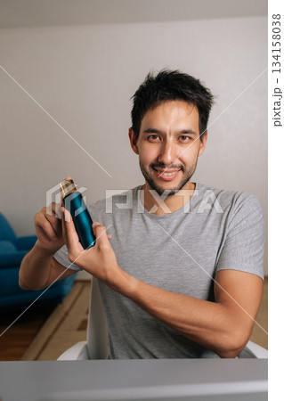 Portrait of man creating beauty content online, doing live review of skincare products for vlog, influencer presenting cosmetics on social media for e-commerce. Concept of male grooming, beauty. 134158038