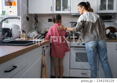 The girl cooks her own breakfast in the kitchen, does the housework, and her mother helps The girl cooks her own breakfast in the kitchen, does the housework, and her mother helps 134158129