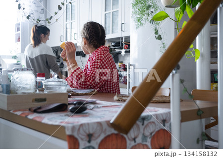 The girl has breakfast in the kitchen in the morning at the table in the company of her mother, morning preparations 134158132