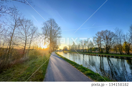 Experience the Serene Sunset Over a Tranquil Canal Pathway During a Perfect Autumn Evening 134158182