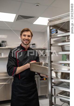 Cook placing square metal pan on stainless steel tray rack 134158469