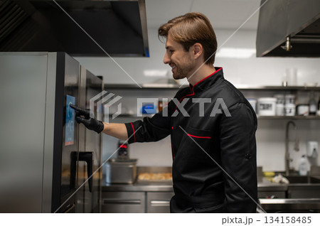 Chef using touchscreen control panel on modern smart oven in kitchen 134158485