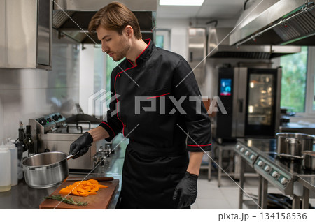 Skilled man working in restaurant standing near stove in culinary space 134158536