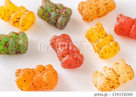 Colorful gummy bears with chili lime seasoning displayed on clean white plate 134159260