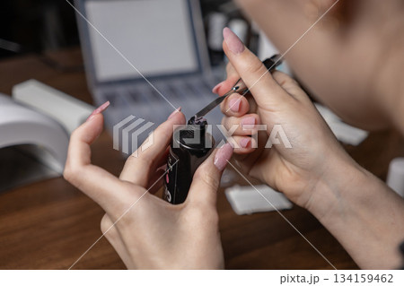 Woman precisely applying polygel for a DIY manicure, carefully shaping elegant long nail extensions using professional tools at home Woman precisely applying polygel for a DIY manicure, carefully shaping elegant long nail extensions using professional tools at home 134159462