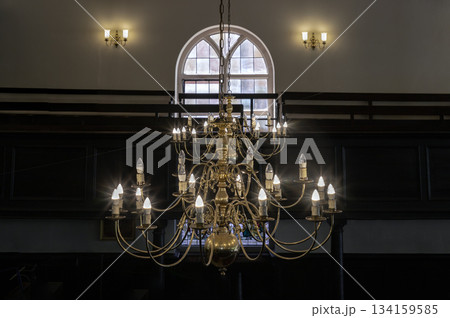 Beautiful view of Chandelier hanging from the ceiling with glass windows in the background of The Church of King Charles the Martyr. Beautiful view of Chandelier hanging from the ceiling with glass windows in the background of The Church of King Charles the Martyr. 134159585