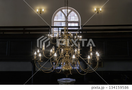 Beautiful view of Chandelier hanging from the ceiling with glass windows in the background of The Church of King Charles the Martyr. Beautiful view of Chandelier hanging from the ceiling with glass windows in the background of The Church of King Charles the Martyr. 134159586